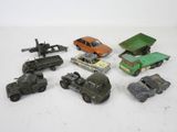 Plusieurs petites voitures et camions sont alignés sur une surface blanche
