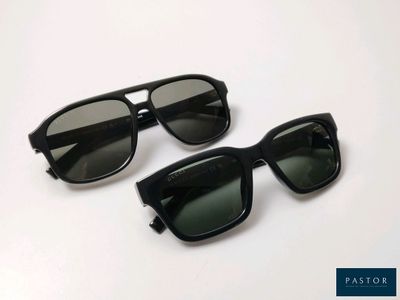 two pairs of black sunglasses sitting on top of a white surface