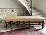 a bench in the middle of a room with a rug on the floor