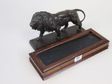 bronze statue of a lion on a wooden base on a white background