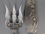 two spoons and a fork with designs on them on a gray surface