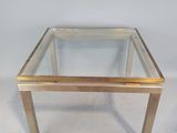une table basse en verre et en laiton sur fond blanc