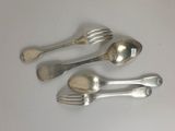 trois cuillères en argent et deux fourchettes en argent posées sur un plateau blanc