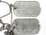 two dog tags attached to a chain on a white surface