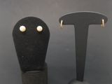two pairs of earrings are sitting on a black display stand