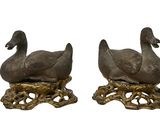 une paire de canards en fonte posés sur des souches d'arbre, sur fond blanc
