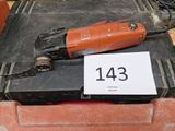 une perceuse électrique rouge et noire posée sur une boîte noire