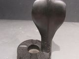 statue of a cobra on a white surface with a black background