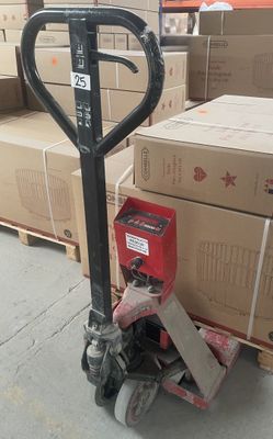 des cartons empilés sur des palettes dans un entrepôt, avec un diable au premier plan
