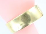 a close up of a gold bracelet on a pink surface