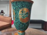 a green vase sitting on a wooden table in a living room