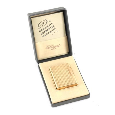 un petit étui à cigarettes en or, dans une boîte posée sur une surface blanche