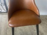 une chaise marron posée sur un parquet