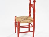 a red wooden chair with a woven seat on a white background