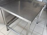 a stainless steel table in a kitchen with a refrigerator in the background