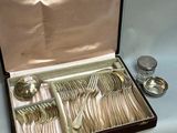 des couverts dans un coffret posé sur une table, à côté d'une cuillère et d'une fourchette