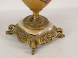 a gold vase on a stand with a red flower on it
