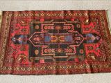 Le tapis posé au sol est rouge et noir et comporte un motif.