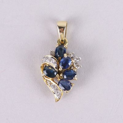 un gros plan d'un pendentif en saphir bleu et diamants posé sur une surface blanche