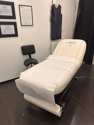 un lit blanc dans une chambre où se trouve une chaise noire