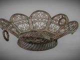 an ornate metal basket with a handle on top of a table