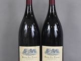 two bottles of red wine sitting on top of a glass table