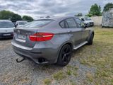 the bmw x6 is parked on the gravel in the parking lot