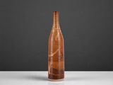 a brown vase sitting on top of a table next to a black wall