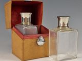 two bottles of perfume sitting in a box on a table