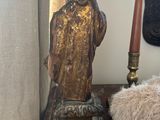 a statue of a man sitting on a table next to a candle