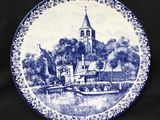 une assiette bleue et blanche sur laquelle est représentée une église