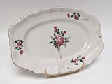a white plate with pink flowers on it on a gold stand