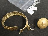 un bracelet, une bague et une boucle d'oreille en or sur un fond noir
