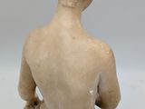 statue of a woman sitting on the ground with her back to the camera