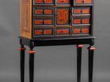 an image of a black and orange cabinet with drawers on legs