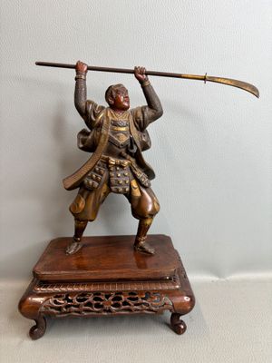 bronze statue of a man holding a sword on a wooden stand