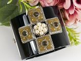 black and white cuff bracelet with pearls and flowers on a white surface