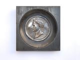 a close up of a coin in a metal tray on a white surface