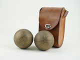 une paire de boules en bois avec un étui en cuir sur fond blanc