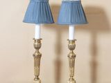 two lamps that are on a table with a picture on the wall in the background