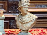 une statue représentant un homme assis sur une table, à côté d'un vase