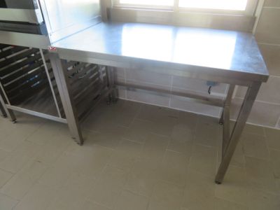 une table en acier inoxydable dans une cuisine équipée d'une cave à vin