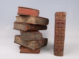 several old books stacked on top of each other next to a tall book