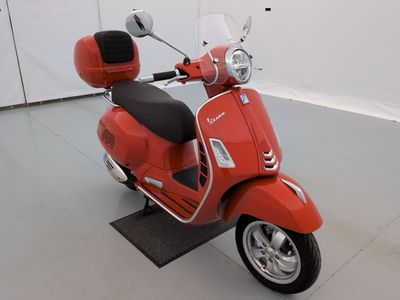 un scooter rouge garé dans une pièce blanche