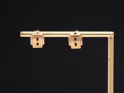 a close up of a pair of gold earrings on a black background