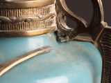 a blue vase with a gold handle on a table