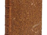 un vieux livre à la couverture brune posé sur une surface blanche