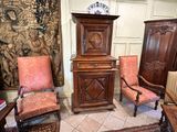 several chairs and a cabinet in a room with a tapestry on the wall