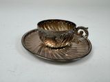 une tasse et une soucoupe en argent posées sur une soucoupe