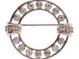 un gros plan d'une broche circulaire sertie de diamants sur fond blanc